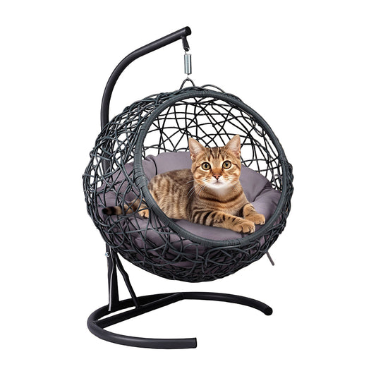 Tabby cat resting in a hanging rattan egg chair cat bed on a black steel stand